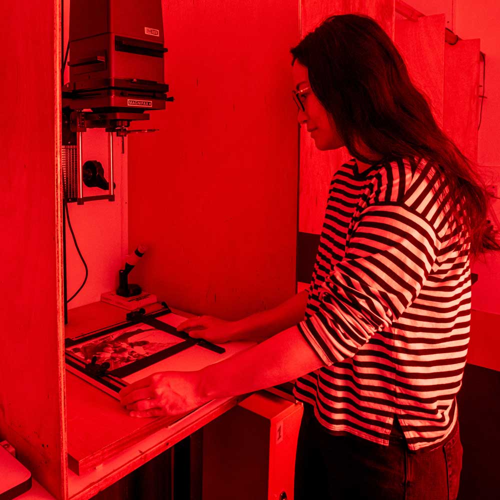 Learner using enlarger in a dark room.