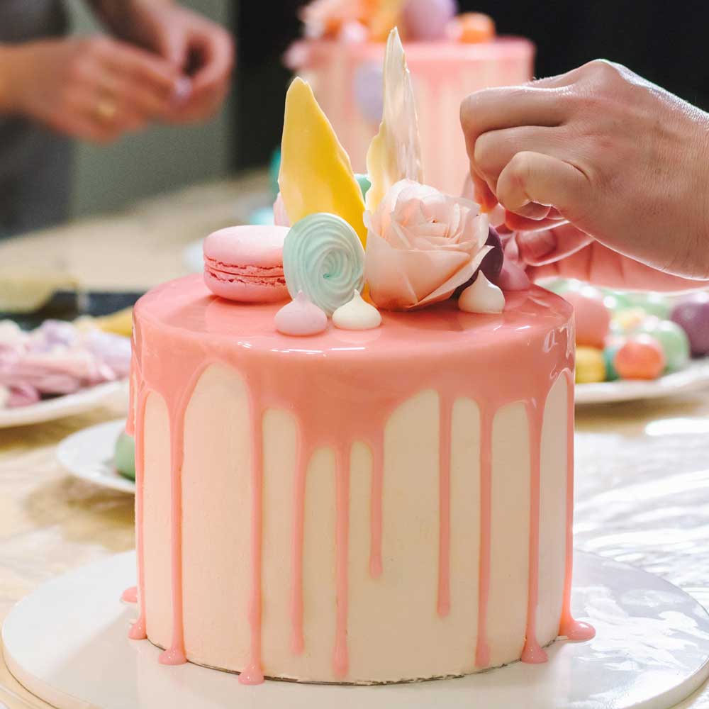 Learner decorating a pink drip cake.