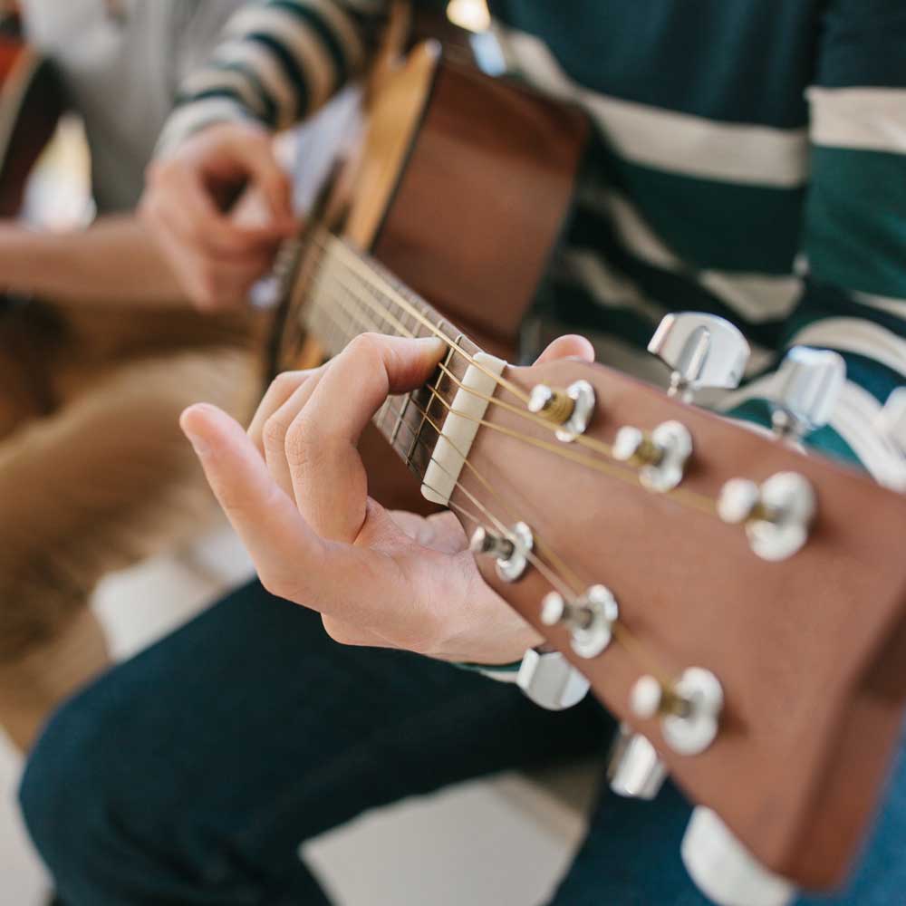 Learner playing an acoustic guitar.