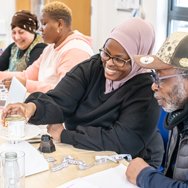 Adult learners practising English skills together in a classroom.