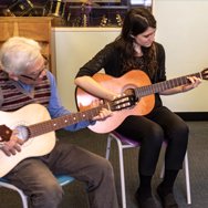 Learners playing acoustic guitars in a class.