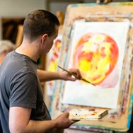 Learner painting at an easel in an art class.