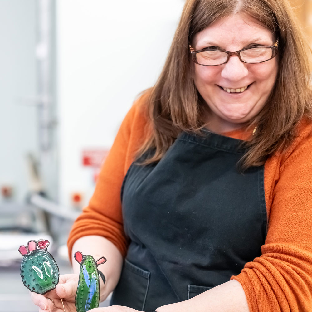 Learner smiling while making glass art pieces