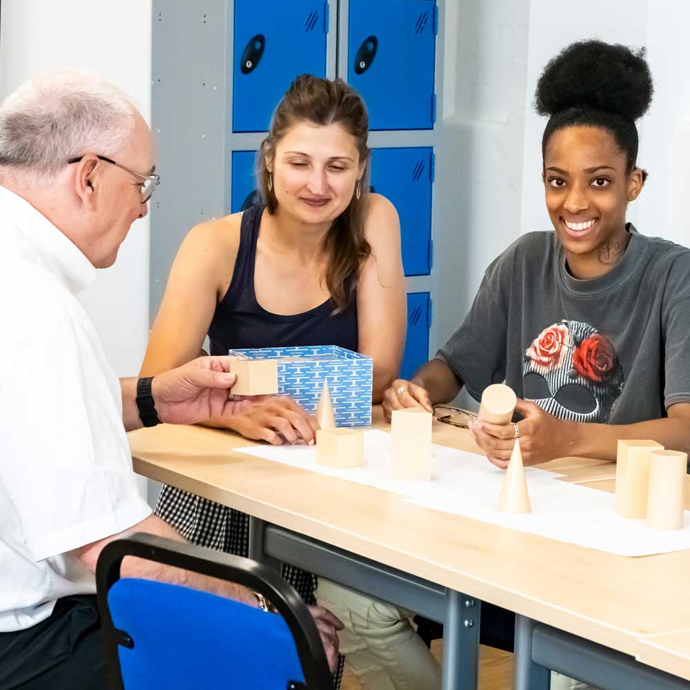 Tutor and learners working at table.