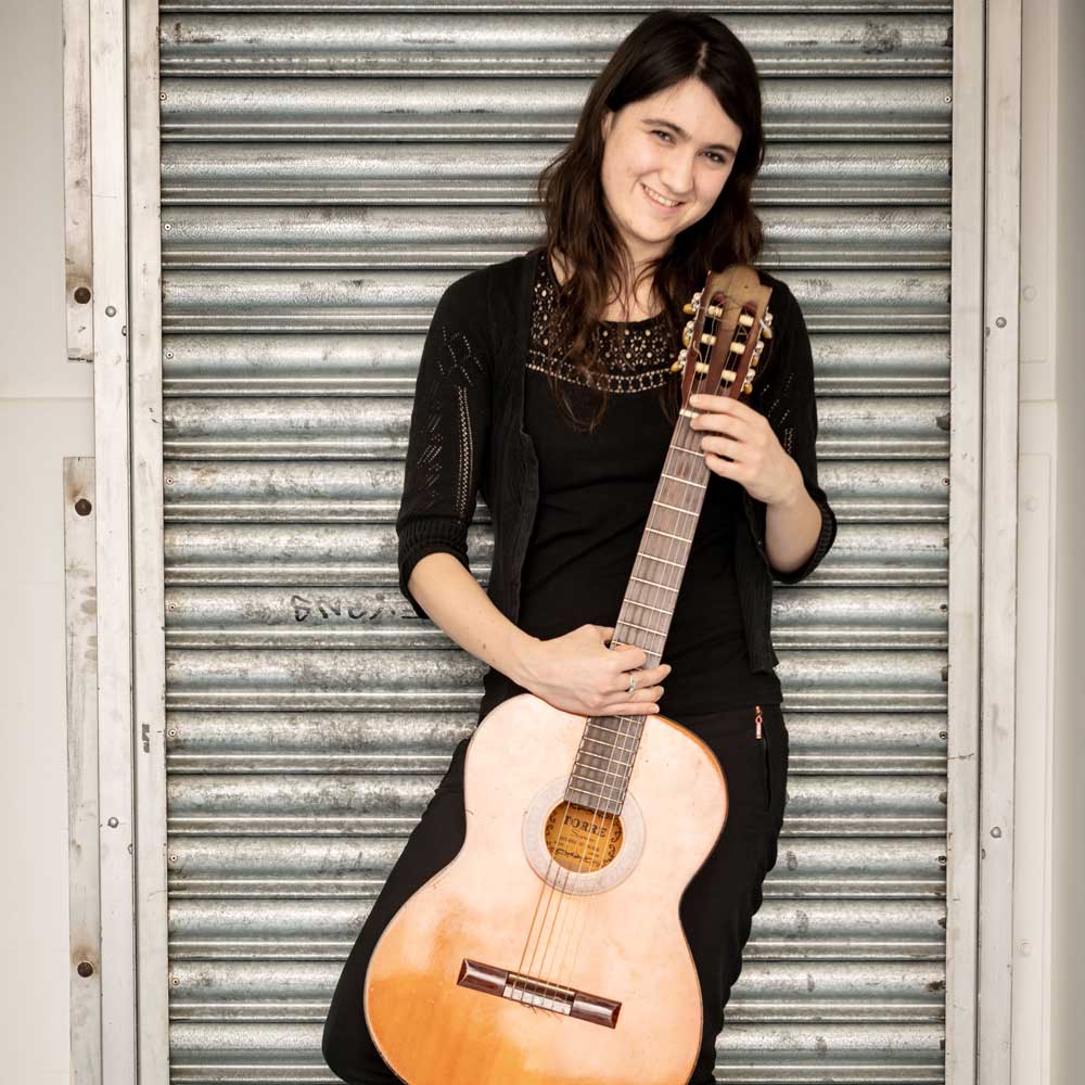 Learner holding an acoustic guitar.