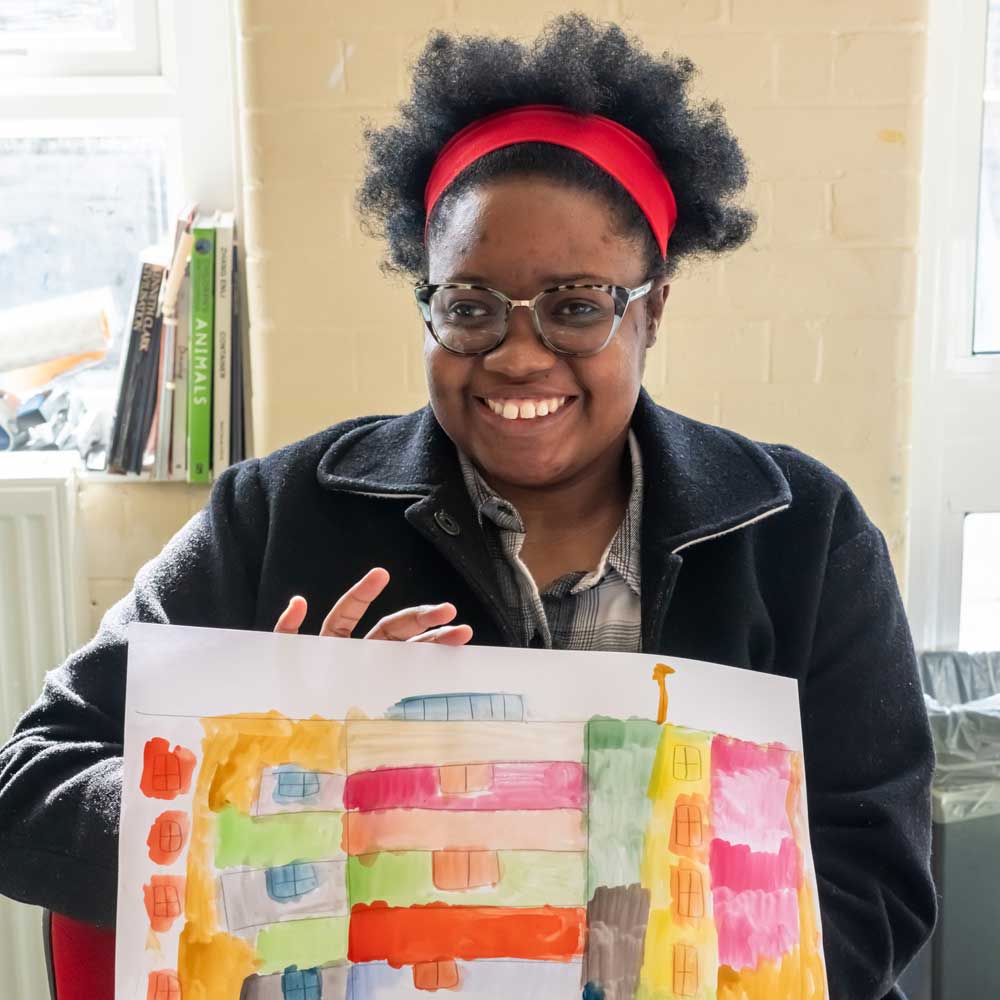Learner proudly holding up a colourful painting during a Supported Learning & Mindlift art session.