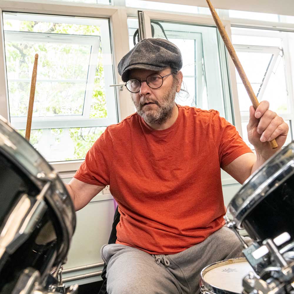 Learner playing the drums during a Health and wellbeing session.