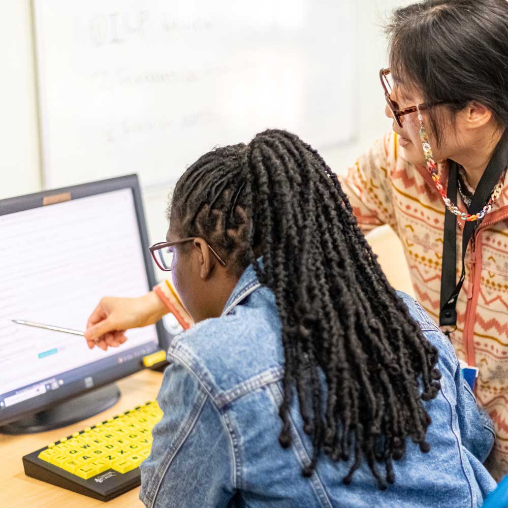 Learners using a computer together during a work skills session.